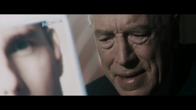 A shocked man with long hair and a baseball cap sitting in a bar, looking surprised.