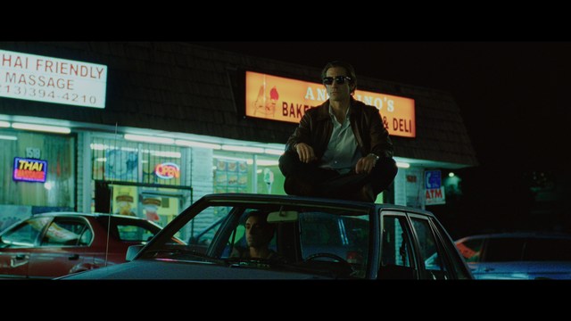 Two characters sitting in a diner, one wearing a blue beanie with 'SNOOGANS' and the other wearing a cap, both looking intently at something off-screen.