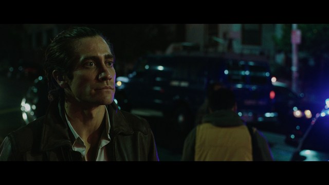 A woman with dark hair and a neutral expression sitting in a retro diner setting.