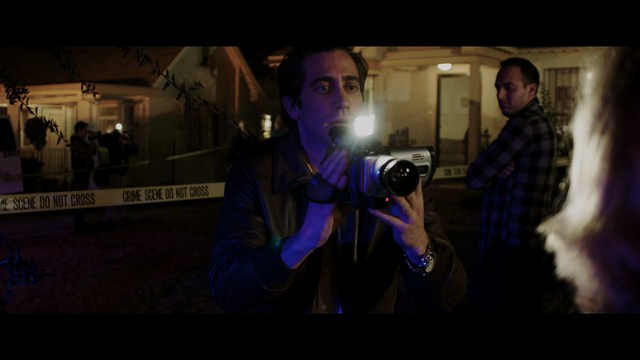 A young man pointing a handgun while seated in a bus, showcasing an intense expression.