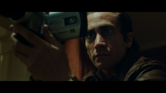 A scene from a movie featuring three characters standing on a bridge with a lush green landscape in the background.