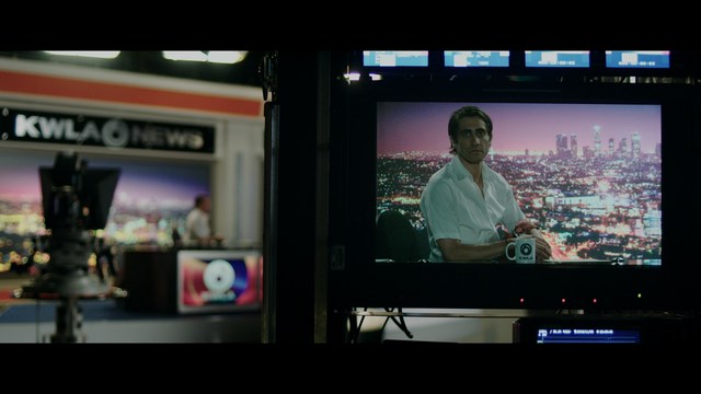 A scene featuring a man with short hair and a beard, wearing a brown jacket and purple shirt, standing outside a restaurant with bright yellow walls and a cartoon cow logo.