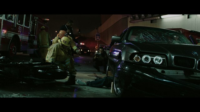 Two men are engaged in conversation at a colorful playground with bright slides in the background.