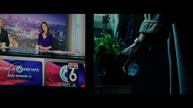 A golden trophy statue of a goblin-like character positioned on a wooden table in an office setting, with large windows and a building facade visible in the background.