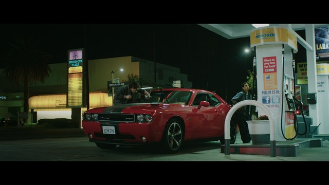 A man with short hair and a beard sits at a table, looking surprised or excited while holding a bottle.