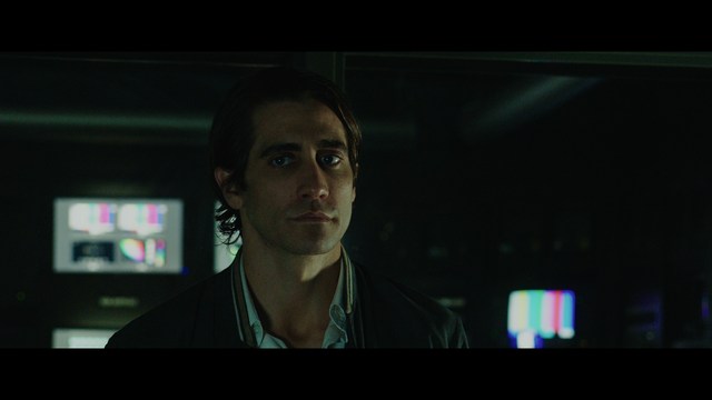 A shocked man with long hair and a baseball cap sitting in a bar, looking surprised.