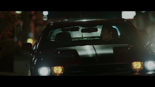 A scene from the film showing two male characters, one in a futuristic helmet and uniform, smiling while the other appears tense, conveying a sense of intrigue.