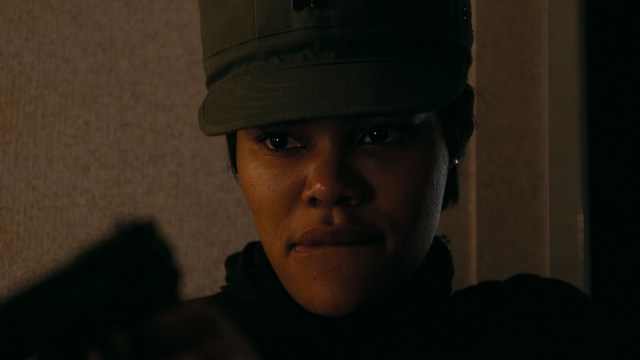 Statue of a smiling figure resembling Jesus, giving a thumbs up gesture, set against a colorful backdrop with signs related to Catholicism.