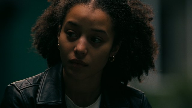 Two characters sitting in a diner, one wearing a blue beanie with 'SNOOGANS' and the other wearing a cap, both looking intently at something off-screen.