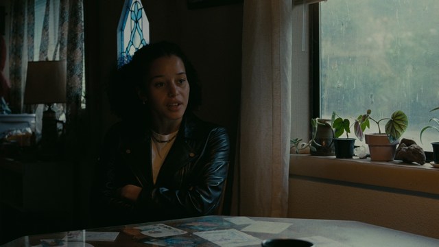 A young man pointing a handgun while seated in a bus, showcasing an intense expression.
