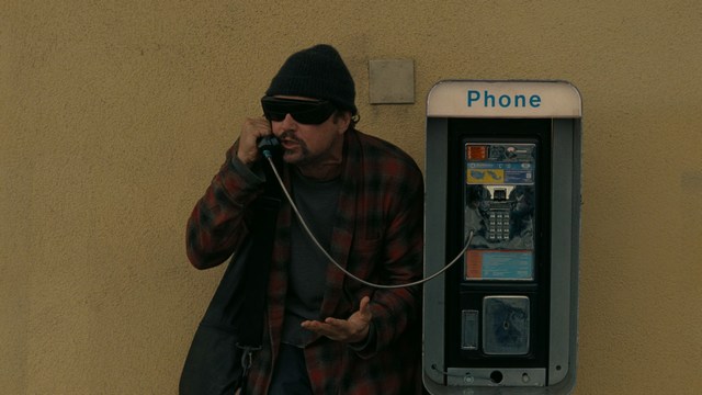 Two men are engaged in conversation at a colorful playground with bright slides in the background.