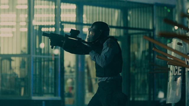 A man with short hair and a beard sits at a table, looking surprised or excited while holding a bottle.