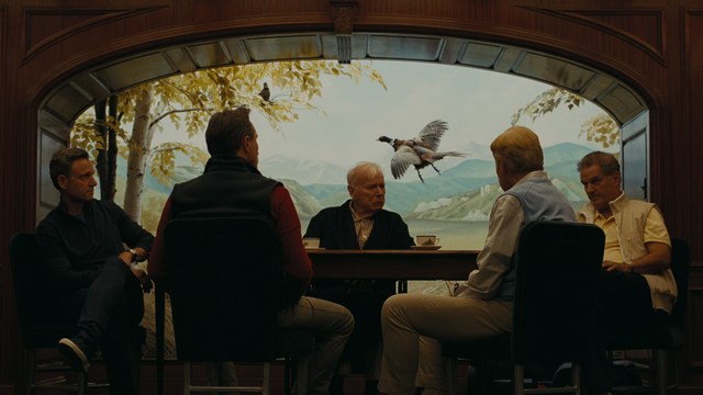 A close-up shot of a man wearing a white suit and a white hat, looking intently at someone in a retail store filled with merchandise.