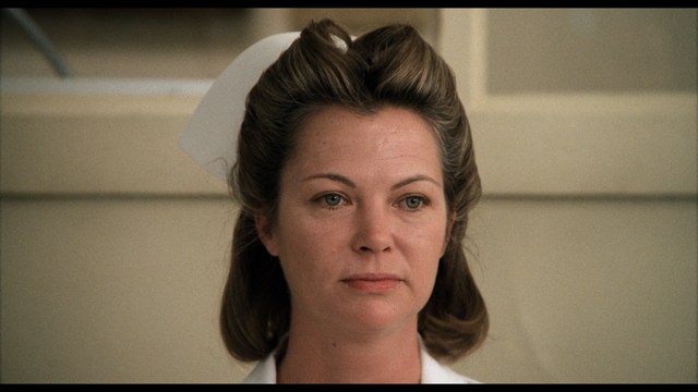 Three young individuals sitting together, two holding hockey sticks, with a casual and intense expression in a domestic setting.