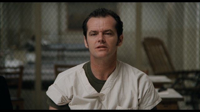 Two characters sitting in a diner, one wearing a blue beanie with 'SNOOGANS' and the other wearing a cap, both looking intently at something off-screen.