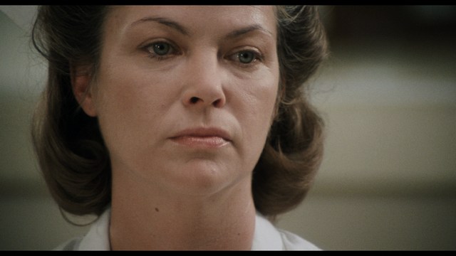 A worried woman stands on a deserted road, looking shocked or distressed as she gazes into the distance.