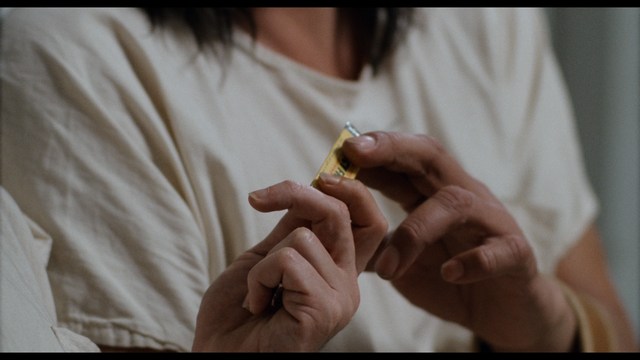 Two young men are looking at something off-camera, standing inside a building with bright lighting and seating areas visible in the background.