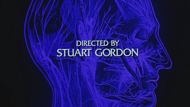 Two male characters sitting in a waiting area, one wearing a black jacket and the other in a maroon hoodie, with popcorn in hand.