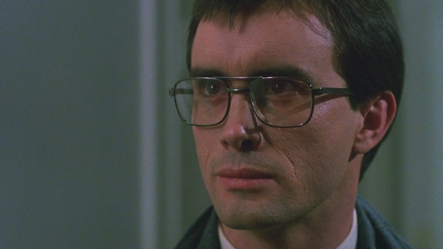 Scene featuring three characters on a roadside, discussing animatedly. A green landscape is visible in the background.