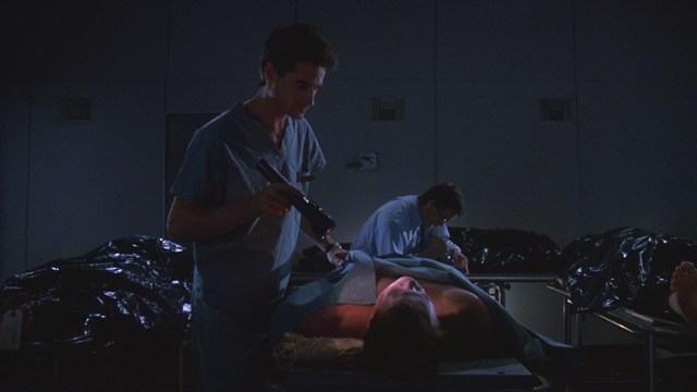 Two men engaged in conversation in a scene from a movie, set against a colorful playground background.