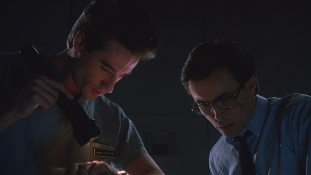 A scene from a film showing five characters in a bar setting, with a colorful background and a bartender visible in the back.