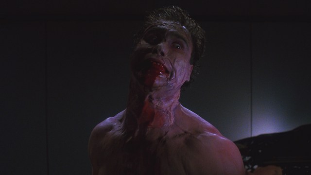 A bronze trophy figure of a cartoonish character with arms outstretched, positioned on a wooden table in a corporate setting, with a large window showcasing a mansion in the background.