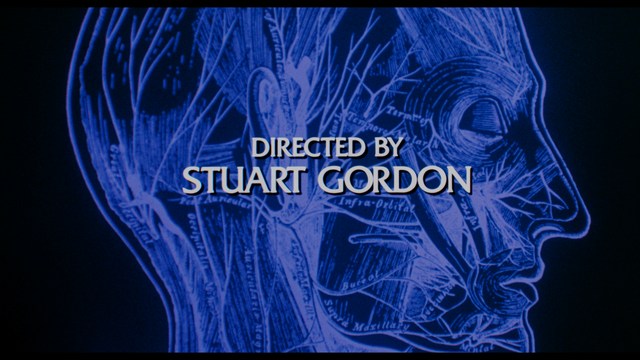 A scene from a movie featuring two young men sitting closely together in an airport waiting area, with one holding a box of popcorn.