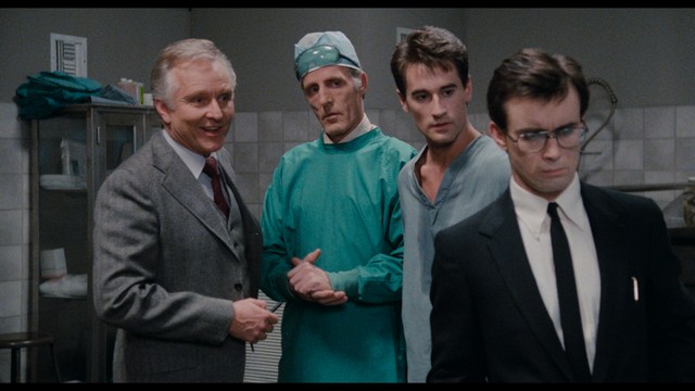 A group of people standing in a church, with a focus on a woman in a striped blazer looking up, while others are holding books or looking ahead.