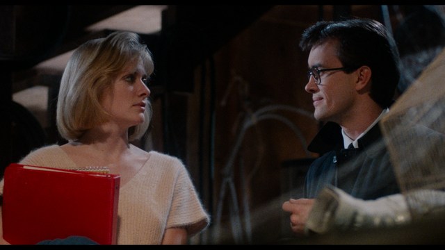 A close-up shot of a man with a distressed expression, featuring dark hair and wearing a blue hoodie, against a softly lit background.