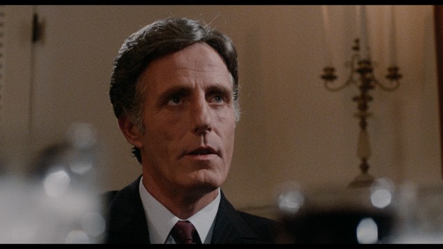 A woman with dark hair and a neutral expression sitting in a retro diner setting.