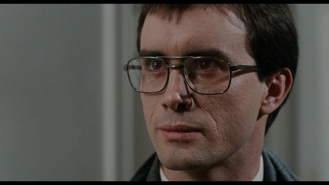 A scene from a movie featuring three characters standing on a bridge with a lush green landscape in the background.