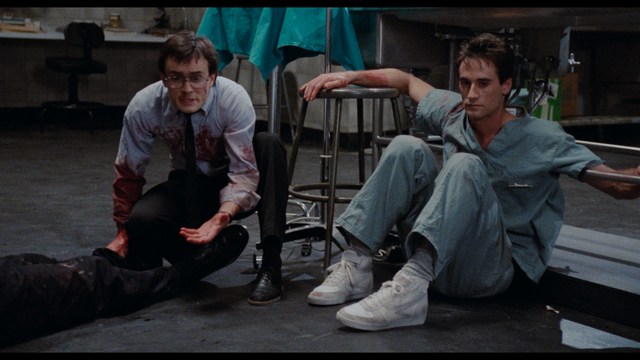 A man with short hair and a beard sits at a table, looking surprised or excited while holding a bottle.