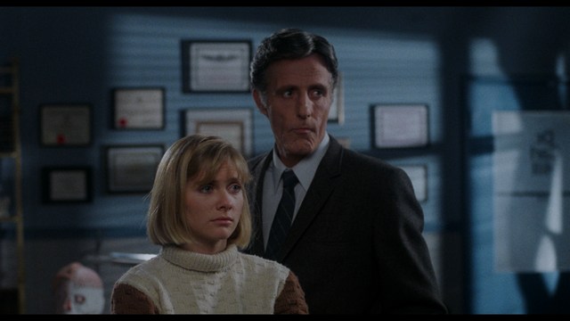 A close-up shot of a man wearing a white suit and a white hat, looking intently at someone in a retail store filled with merchandise.