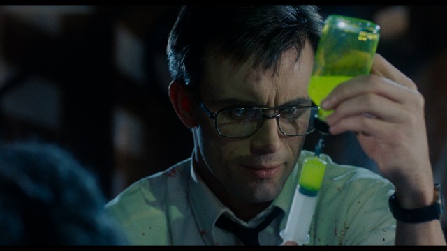 A woman seated at a restaurant table, thoughtfully resting her chin on her hand while reading a newspaper. Blurred figures of two people can be seen in the background.