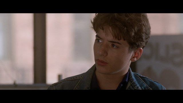 Four anthropomorphic turtles in ninja attire stand in a dimly lit room, while a humanoid character with fur sits nearby.