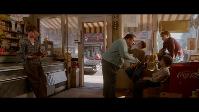 Two characters sitting in a diner, one wearing a blue beanie with 'SNOOGANS' and the other wearing a cap, both looking intently at something off-screen.