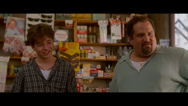 A woman with dark hair and a neutral expression sitting in a retro diner setting.