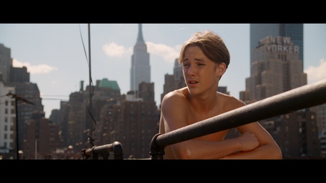 A worried woman stands on a deserted road, looking shocked or distressed as she gazes into the distance.