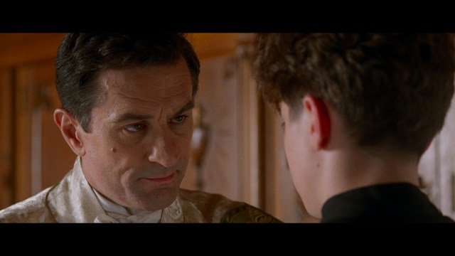 Two men are engaged in conversation at a colorful playground with bright slides in the background.