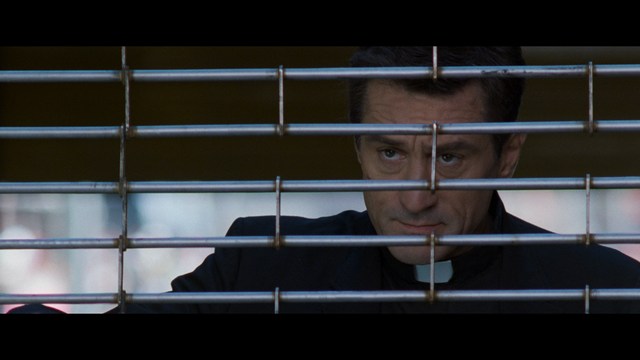 A scene featuring five characters in a bar setting, with a focus on their expressions and interactions. The backdrop includes bar shelves with bottles and a bartender visible in the background.