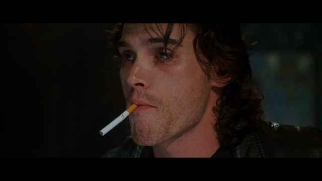 Aerial view of futuristic skyscrapers with cars driving vertically up the side of a building, showcasing a modern urban landscape.