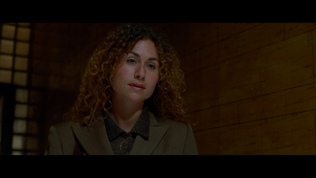 A close-up of an elderly man with a beard and white attire, appearing serious and contemplative, set against a colorful, futuristic background.