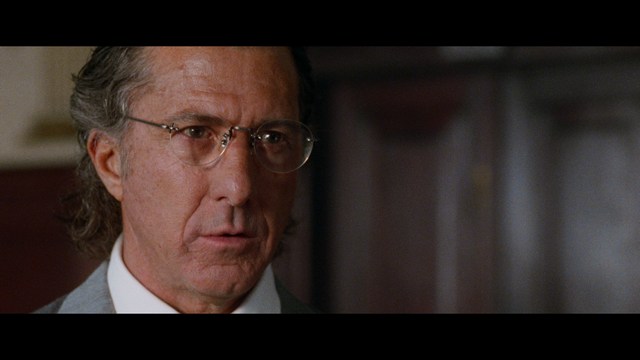 A close-up of an elderly man with a beard and white attire, appearing serious and contemplative, set against a colorful, futuristic background.