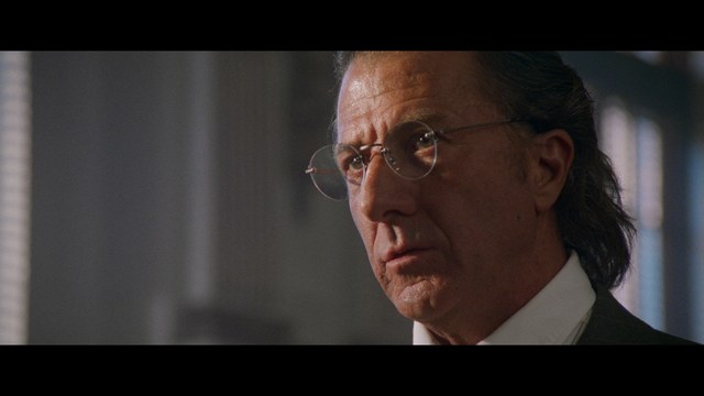 A close-up of an elderly man with a beard and white attire, appearing serious and contemplative, set against a colorful, futuristic background.