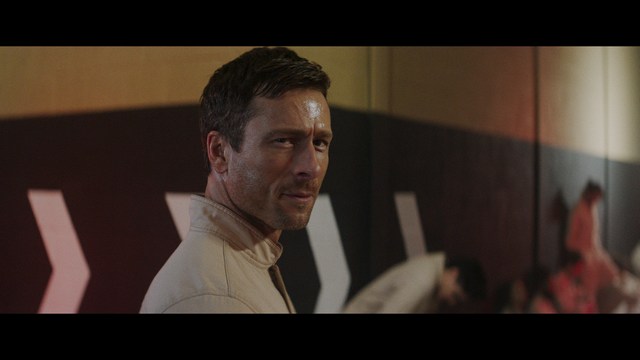 Three young individuals sitting together, two holding hockey sticks, with a casual and intense expression in a domestic setting.