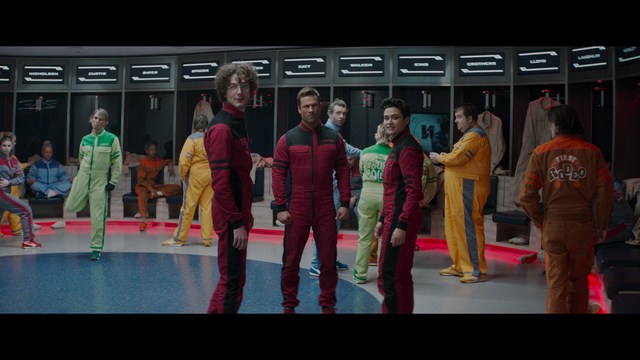 A close-up shot of a man with a distressed expression, featuring dark hair and wearing a blue hoodie, against a softly lit background.