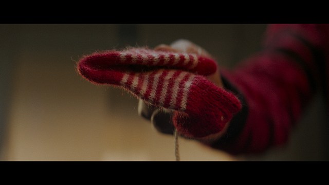 A scene from a movie featuring three characters standing on a bridge with a lush green landscape in the background.