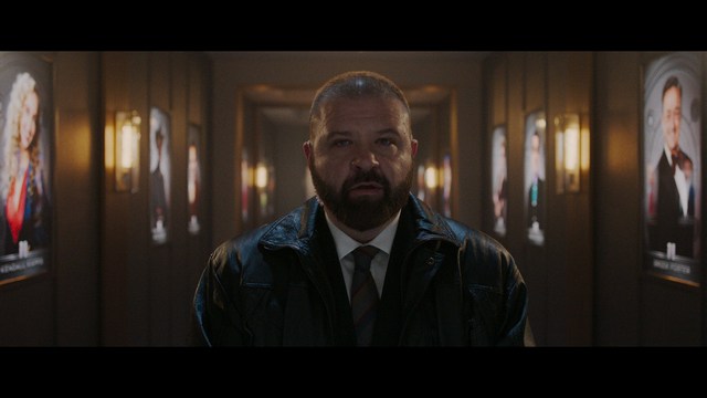 A worried woman stands on a deserted road, looking shocked or distressed as she gazes into the distance.