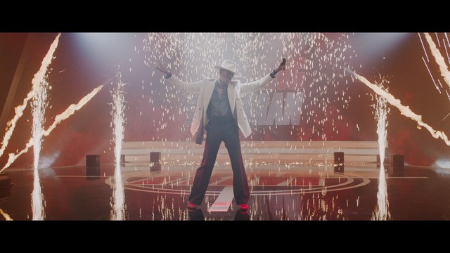 Two men are engaged in conversation at a colorful playground with bright slides in the background.