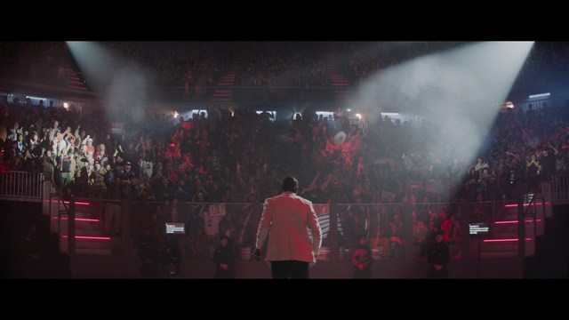 A scene featuring five characters in a bar setting, with a focus on their expressions and interactions. The backdrop includes bar shelves with bottles and a bartender visible in the background.